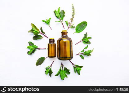 Holy Basil Essential Oil in a Glass Bottle with Fresh Holy Basil white wooden background.