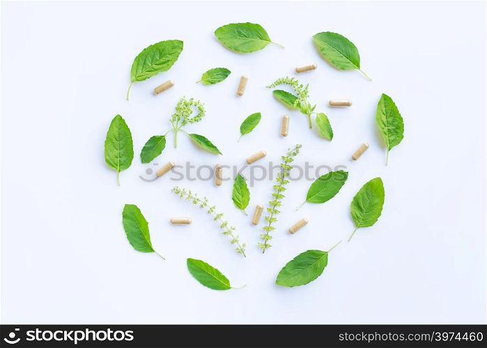 Holy basil leaves and flower with herbal capsules on white background.