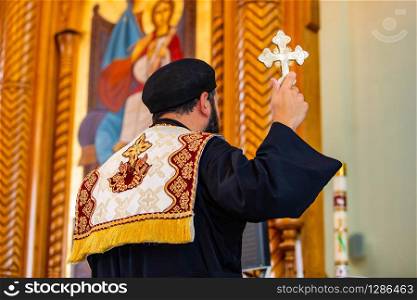 Holy father priest holding a golden cross symbol during sacred ceremony. Holy father priest holding a golden cross symbol during ceremony