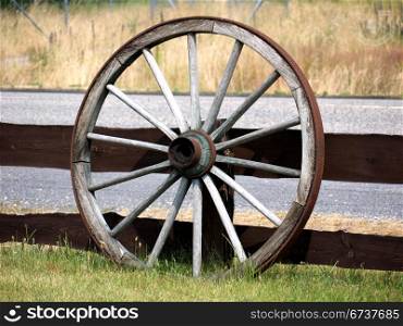 Holzrad. old wagon wheel in front of a wooden fence