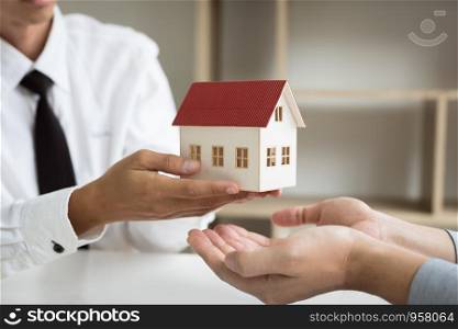Home agents are giving house gifts to new home buyers in office room.