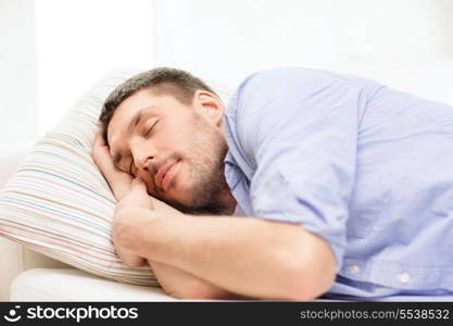 home and happiness concept - calm young man lying on sofa at home