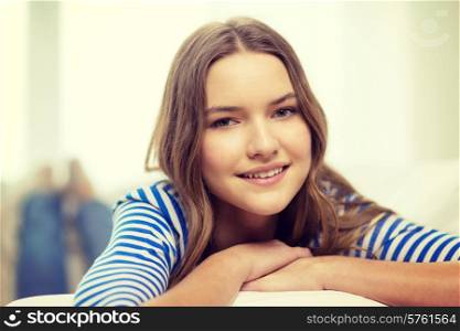 home and happiness concept - smiling teenage girl lying on sofa at home