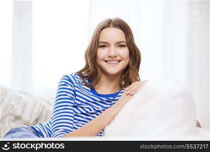 home and happiness concept - smiling teenage girl sitting on sofa at home