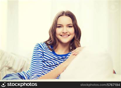 home and happiness concept - smiling teenage girl sitting on sofa at home