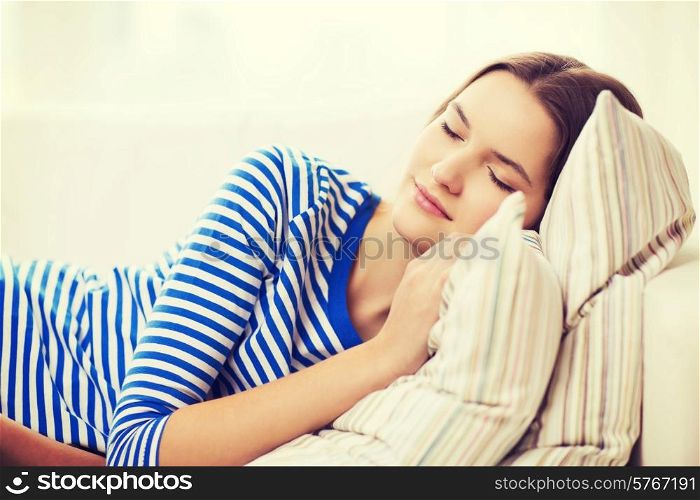 home and happiness concept - smiling teenage girl sleeping on sofa at home