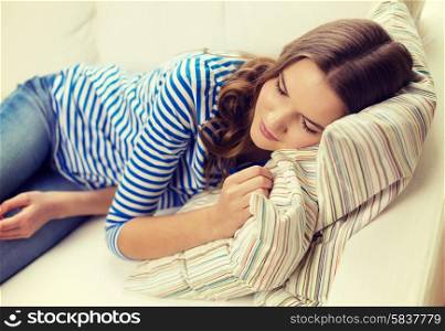 home and happiness concept - smiling teenage girl sleeping on sofa at home