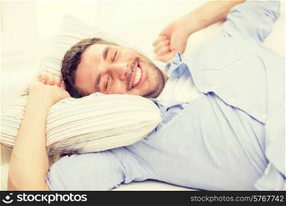 home and happiness concept - smiling young man lying on sofa at home
