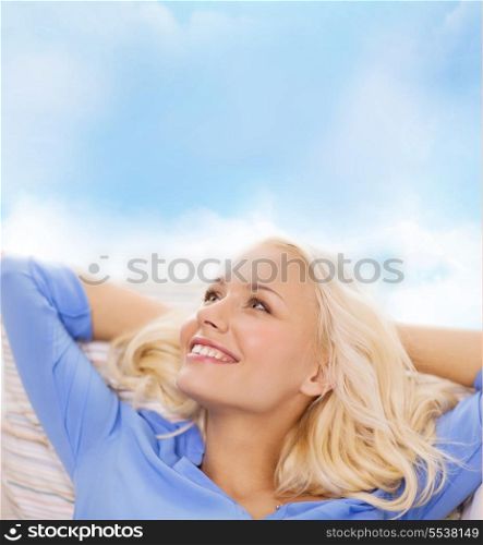 home and happiness concept - smiling young woman lying on sofa