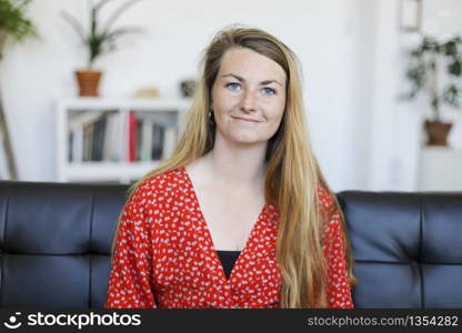 home and happiness concept - smiling young woman lying on sofa at home