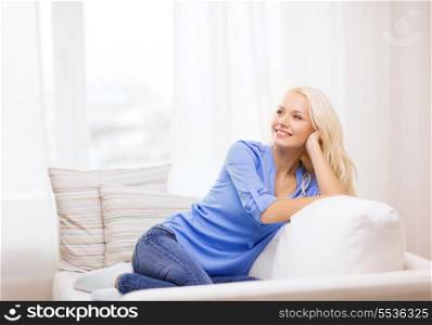 home and happiness concept - smiling young woman lying on sofa at home