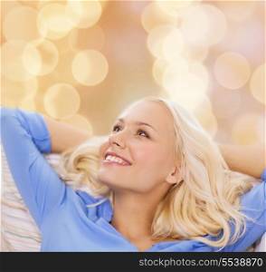 home and happiness concept - smiling young woman lying on sofa at home