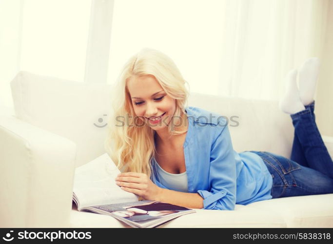 home and leasure concept - smiling woman lying on couch and reading magazine at home