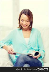 home and leasure concept - smiling woman reading magazine at home. smiling woman reading magazine at home