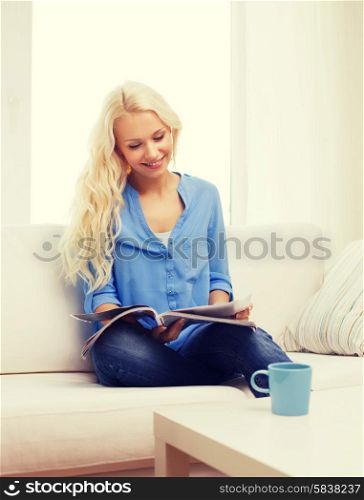 home and leasure concept - smiling woman with cup of coffee or tea reading magazine at home