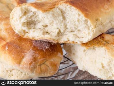 Home-baked Italian-style bread batons, one of them broken to show the texture of the crumb.