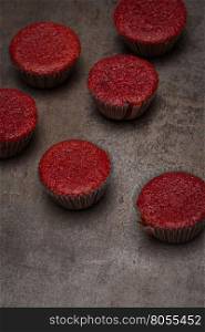 Home baked red beetroot muffins on dark metal textured background.