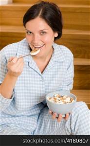 Home breakfast happy woman in pajamas eating cereals on stairs