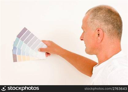 Home decorating mature male painter choose color swatches white wall