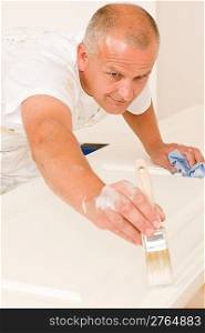 Home decorating mature man painting white door with paint brush