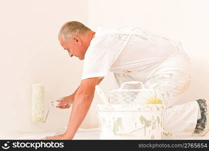 Home decorating mature man painting white wall with roller