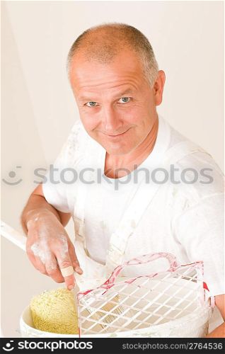 Home decorating mature man with paint roller, grid and bucket