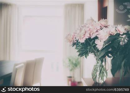 Home decoration with fresh pink peonies bunch in glass vase at living room background, Nostalgic retro toned