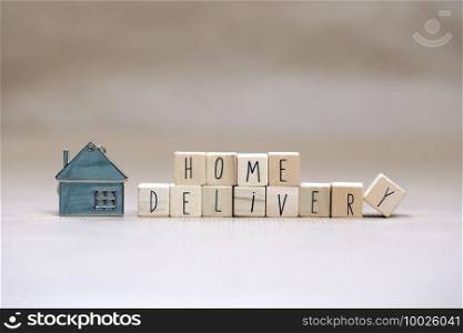 Home delivery text with wooden cubes and little miniature house on blurred background, Business, stay home for Covid-19, we deliver concept background copy space. Home delivery text with wooden cubes and little miniature house on blurred background, Business, stay home for Covid-19, we deliver concept background