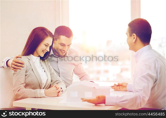 home, design and architecture concept - couple looking at blueprint and model of their new house at office
