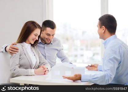 home, design and architecture concept - couple looking at blueprint and model of their new house at office