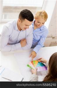 home, design and architecture concept - smiling couple looking at blueprint and color samples at office