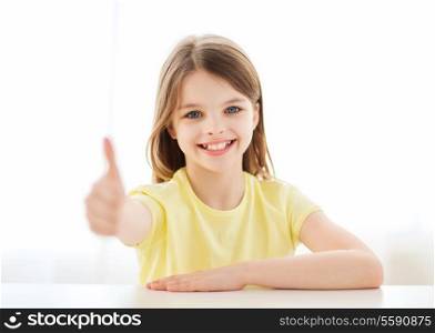 home, education, happiness and people concept - beautiful little girl at home showing thumbs up