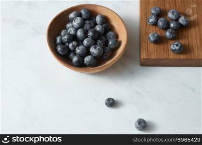 Home grown natural fresh berries for cooking sweet desserts on kitchen table. Concept of healthy homemade food.. Summer organic natural sweet blueberries in a wooden plate on a white. Copy space.