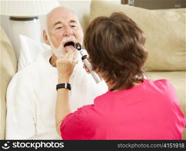 Home health care nurse looks in a patient&rsquo;s throat.