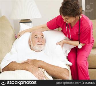 Home health nurse fluffs an elderly patient&rsquo;s pillow.