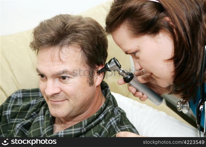 Home health nurse using an otoscope to look in her patient&rsquo;s ears.
