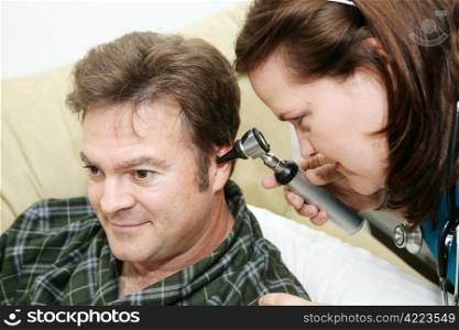 Home health nurse using an otoscope to look in her patient&rsquo;s ears.