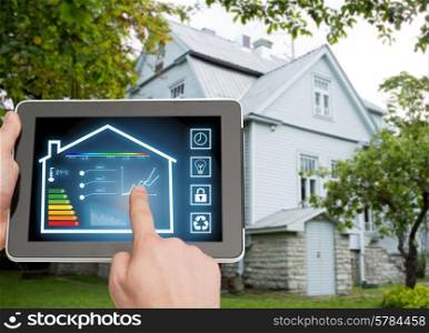 home, housing, people and technology concept - close up of man hands pointing finger to tablet pc computer and regulating room temperature over house background