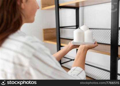 home improvement and decoration and people concept - close up of woman placing candles to shelf. close up of woman decorating home with candles