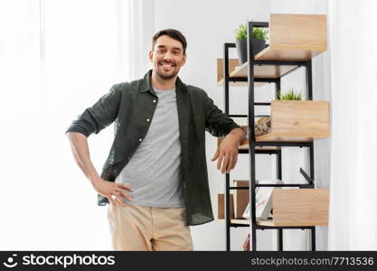 home improvement and decoration and people concept - happy smiling man standing at shelf at home. happy smiling man standing at shelf at home