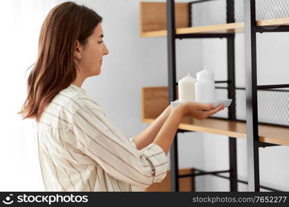 home improvement and decoration and people concept - woman placing candles to shelf. woman decorating home with candles