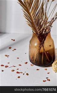 home improvement and decoration concept - still life of decorative dried flowers in brown glass vase and petals. decorative dried flowers in glass vase and petals