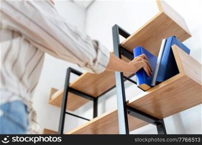 home improvement and people concept - close up of woman arranging books on shelving. woman arranging books on shelving at home