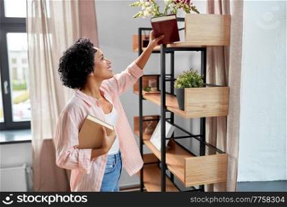 home improvement and people concept - happy smiling woman arranging books on shelving. smiling woman arranging books on shelving at home