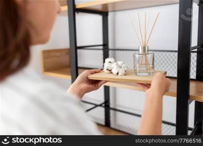 home improvement, decoration and people concept - close up of woman placing aroma reed diffuser to shelf. woman placing aroma reed diffuser to shelf home
