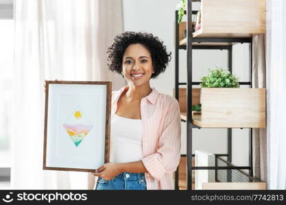 home improvement, decoration and people concept - happy smiling woman holding picture in frame at shelf. happy woman holding picture in frame at home