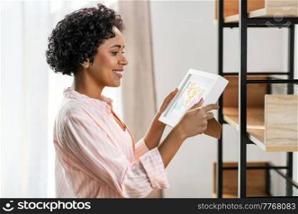 home improvement, decoration and people concept - happy smiling woman holding picture in frame at shelf. happy woman holding picture in frame at home