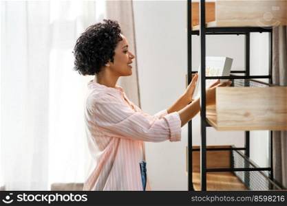 home improvement, decoration and people concept - happy smiling woman holding picture in frame at shelf. happy woman holding picture in frame at home