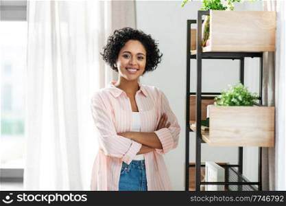 home improvement, decoration and people concept - happy smiling woman standing at shelf at home. happy smiling woman standing at shelf at home