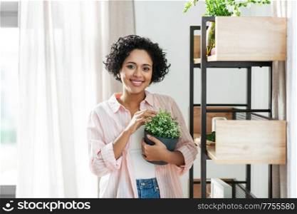 home improvement, decoration and people concept - happy smiling woman with flower or houseplant at shelf. woman decorating home with flower or houseplant